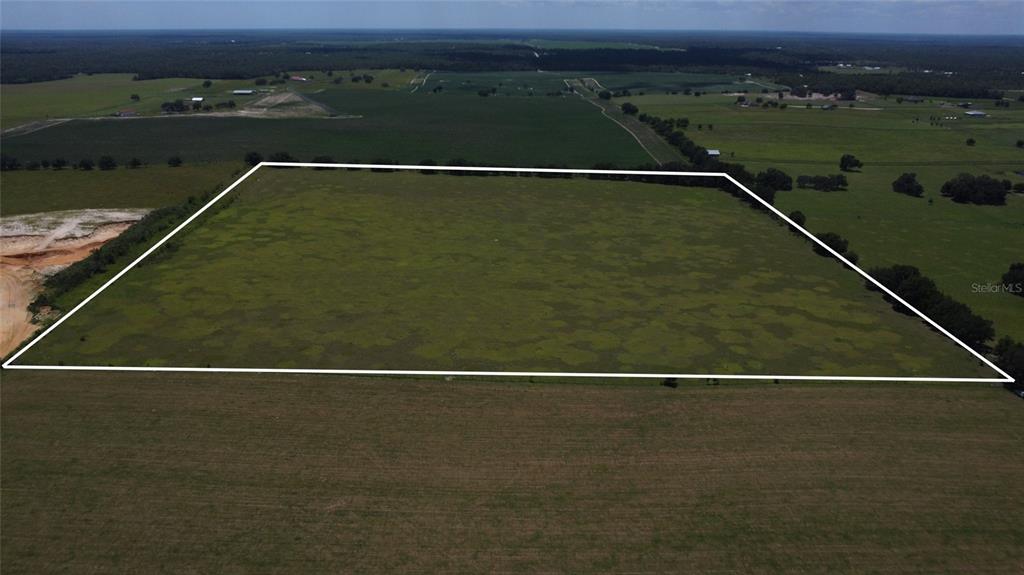 An aerial view shows a large, rectangular plot of open green land outlined in white — 2000 NW 225TH AVENUE, DUNNELLON, FL