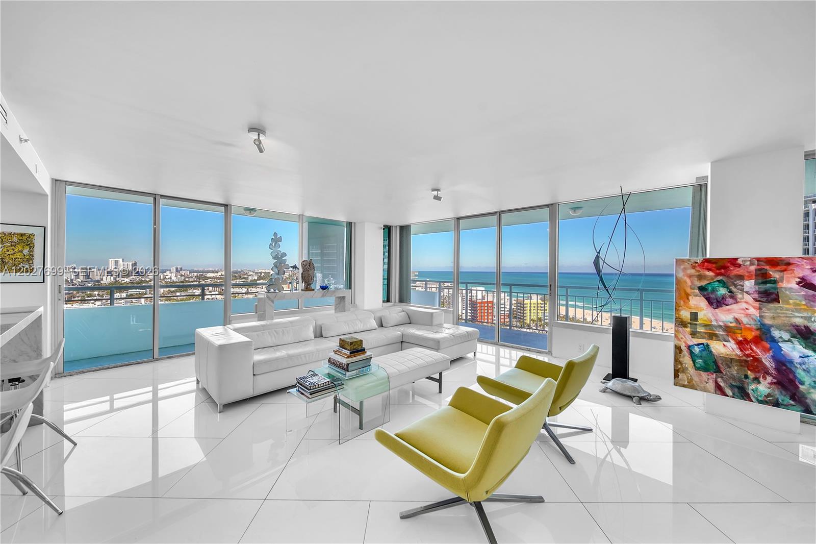 A modern living room features white tile floors, a white sectional, and floor-to-ceiling ocean views — 400 S Pointe Dr # 2310, Miami Beach FL 33139, MIAMI BEACH, FL
