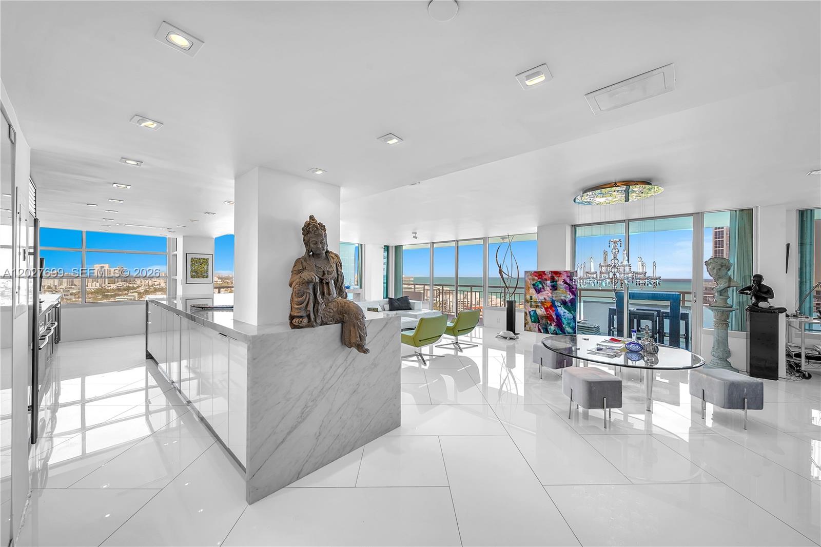 A modern, open-concept living and dining area features white marble floors, floor-to-ceiling windows, and ocean views — 400 S Pointe Dr # 2310, Miami Beach FL 33139, MIAMI BEACH, FL