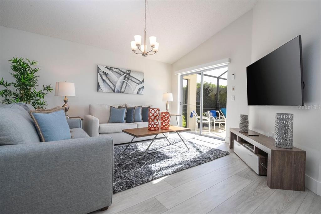 A living room features a gray sofa, a coffee table, and a wall-mounted television — 2673 EMERALD ISLAND BOULEVARD, KISSIMMEE, FL
