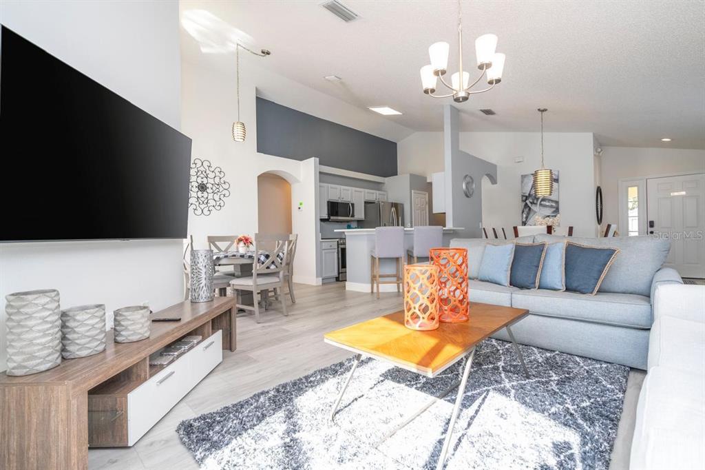 A living room with a grey sofa, wood coffee table, and open kitchen area — 2673 EMERALD ISLAND BOULEVARD, KISSIMMEE, FL