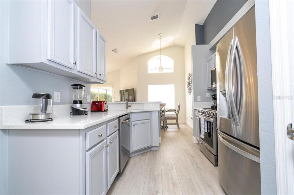 A kitchen with light blue cabinets, stainless steel appliances, and white countertops — 2673 EMERALD ISLAND BOULEVARD, KISSIMMEE, FL