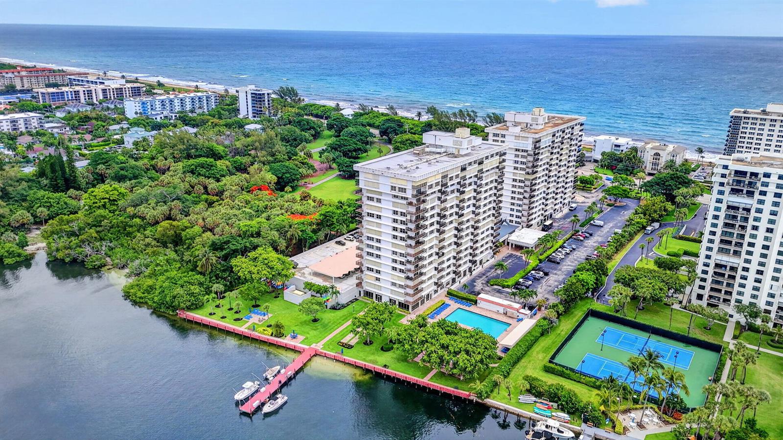 An aerial view shows two high-rise apartment buildings near a waterway, tennis courts, and ocean — 2121 N Ocean Boulevard # 705e, Boca Raton FL 33431, BOCA RATON, FL