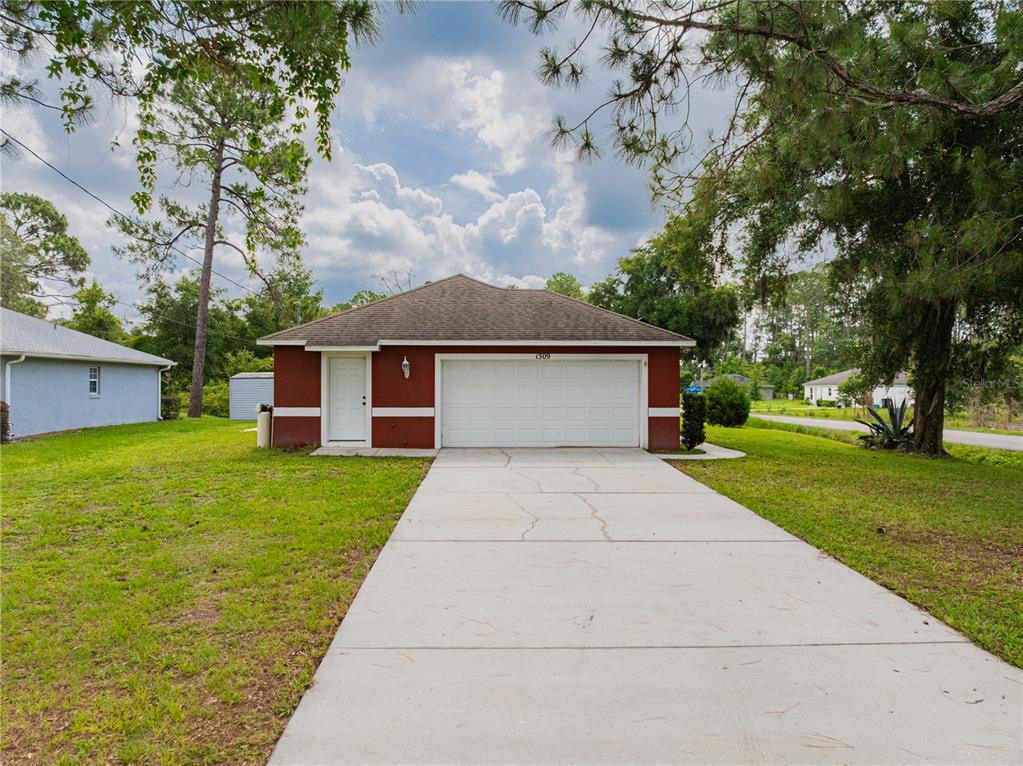 A red single-story house features a white garage door, a side door, and a driveway — 1509 WEST PARKWAY, DELAND, FL
