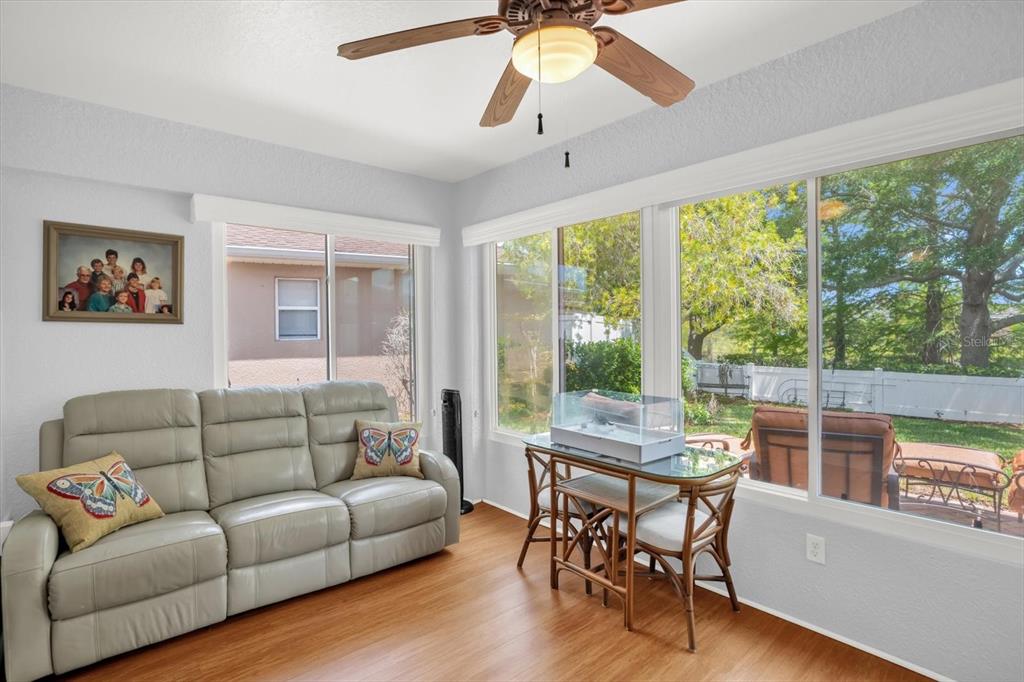 A sunroom features a light-colored leather sofa, a glass-top table, and large windows — 3440 GRENVILLE DRIVE, WINTER HAVEN, FL