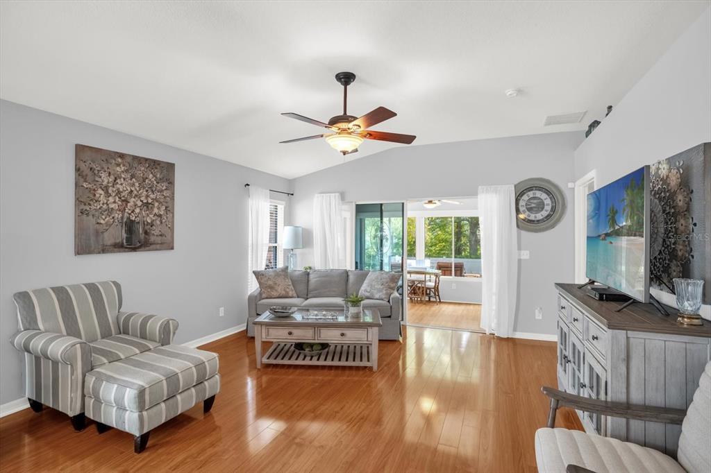 A living room features light gray walls, hardwood flooring, a ceiling fan, and sliding doors — 3440 GRENVILLE DRIVE, WINTER HAVEN, FL