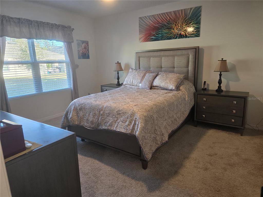 A bedroom features a tufted headboard, matching nightstands, a patterned bedspread, and a window — 532 EMILY GLEN STREET, DELAND, FL