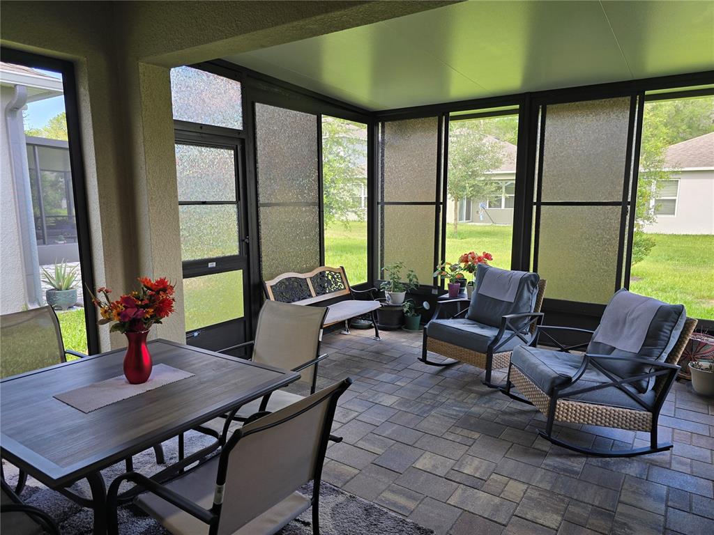 A covered patio features a dining set, rocking chairs, and screened walls with textured glass — 532 EMILY GLEN STREET, DELAND, FL