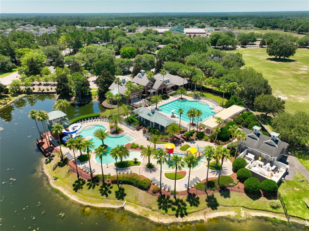 An aerial view shows a community pool complex with water slides, a clubhouse, and landscaping — 585 RUNNING WOODS STREET, ORANGE PARK, FL