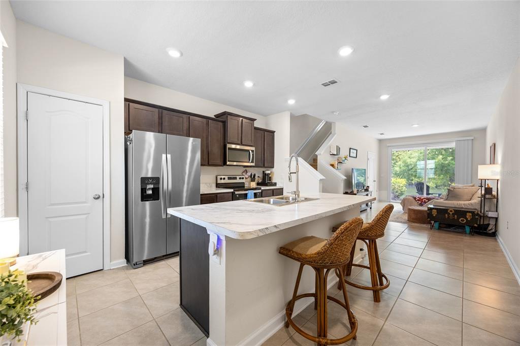 A kitchen with dark cabinets, stainless steel appliances, and a white marble-topped island — 585 RUNNING WOODS STREET, ORANGE PARK, FL