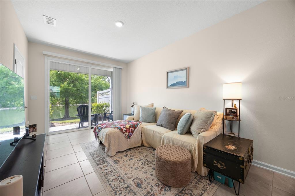 A living room features a sectional sofa, a patterned rug, and a sliding glass door — 585 RUNNING WOODS STREET, ORANGE PARK, FL