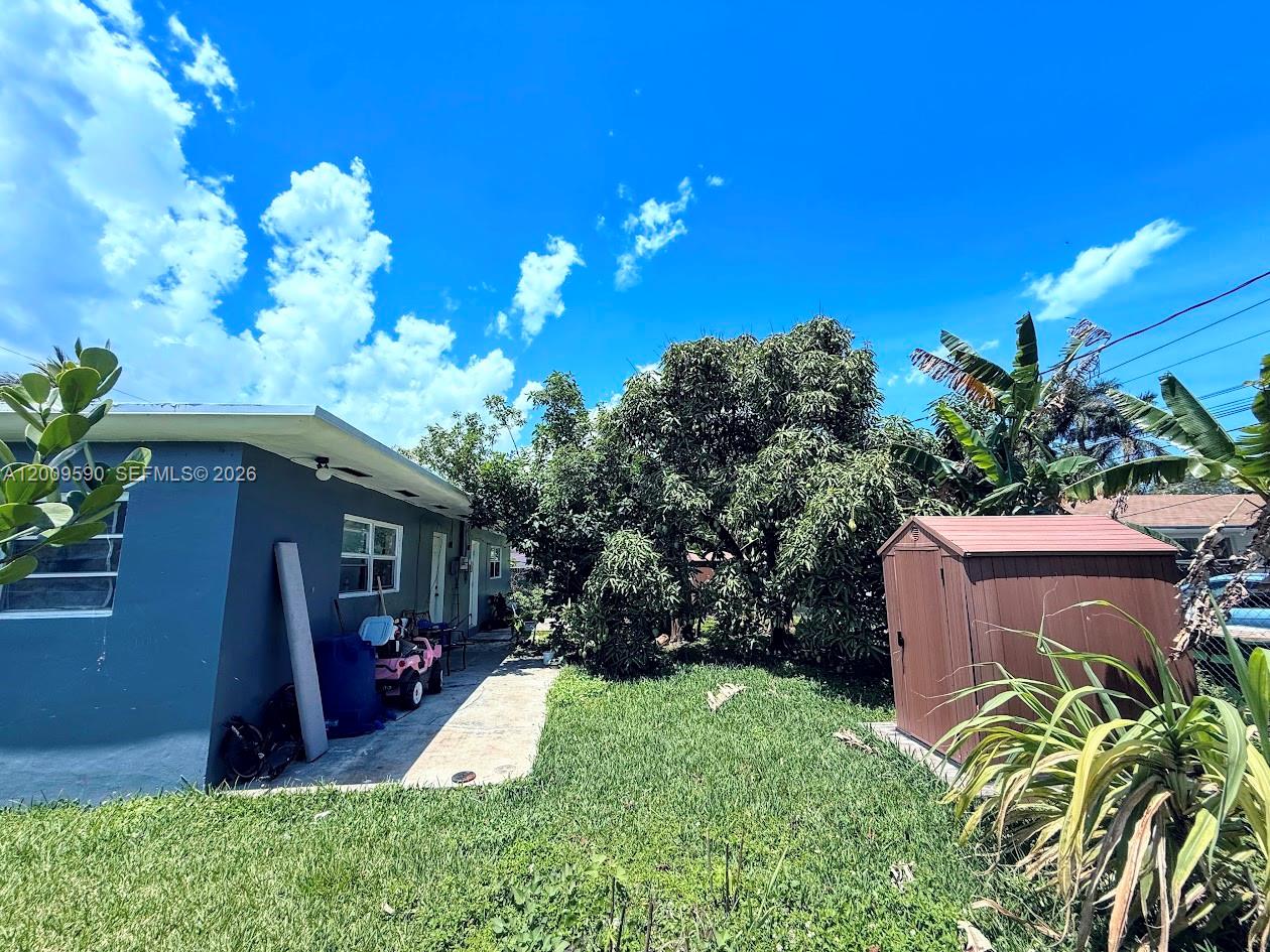 The exterior of a house features a gray wall, a lawn, a shed, and trees — 14615 NE 14th Ave, Miami FL 33161, MIAMI, FL