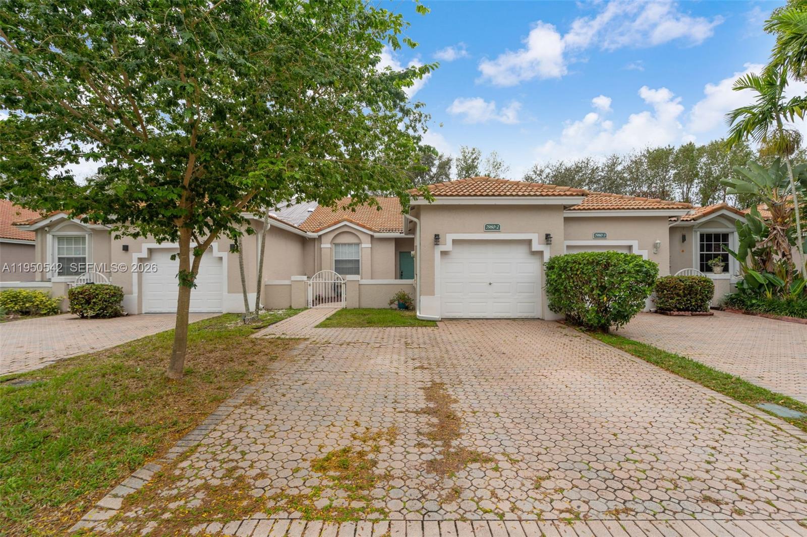 A beige, single-story residential building with two garage doors and a paved driveway — 7980 S Aragon Blvd # 2, Sunrise FL 33322, SUNRISE, FL