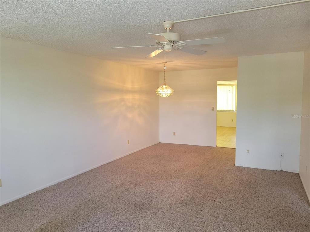 An empty room features beige carpeting, white walls, a ceiling fan, and a hanging light — 4890 BAY STREET NE UNIT 336, ST PETERSBURG, FL