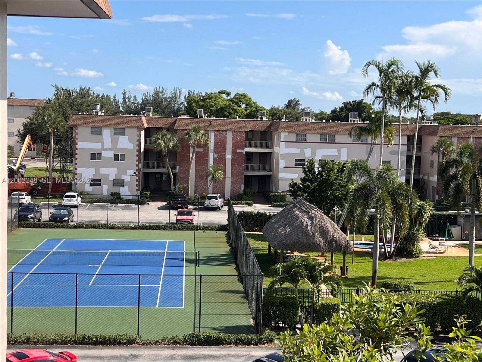 An exterior view shows a tennis court, a thatched-roof gazebo, and an apartment building — 8101 SW 24th Ct # 406, Davie FL 33324, DAVIE, FL