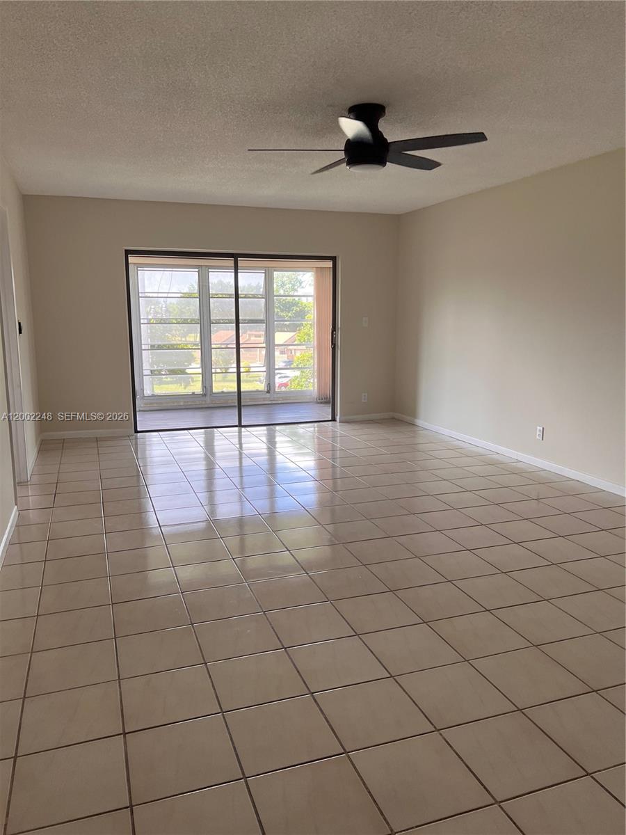 An empty room features light-colored floor tiles, a ceiling fan, and sliding glass doors — 8101 SW 24th Ct # 406, Davie FL 33324, DAVIE, FL