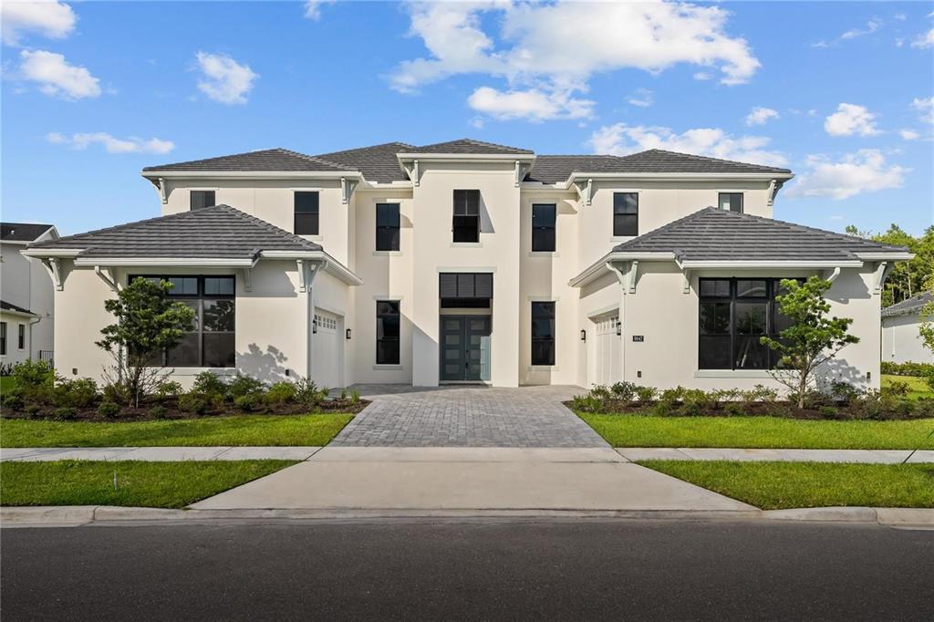 A two-story, white stucco house with a gray tile roof and a paved driveway — 9847 LAUREL BERRY DRIVE, ORLANDO, FL