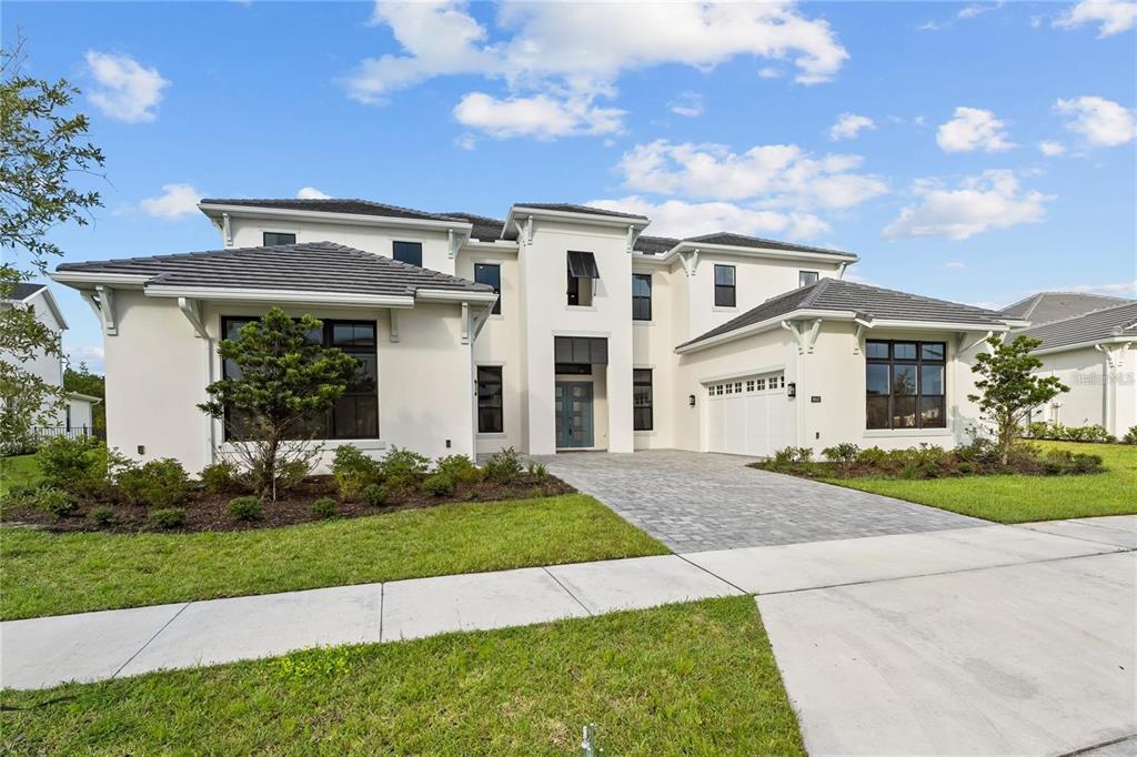 A two-story modern house with white stucco walls, a gray tile roof, and a driveway — 9847 LAUREL BERRY DRIVE, ORLANDO, FL