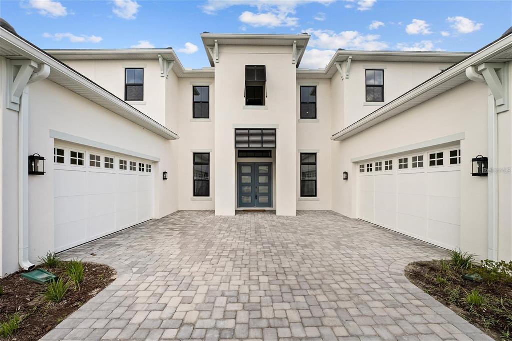A two-story white stucco house features a central entryway, two garages, and a paved driveway — 9847 LAUREL BERRY DRIVE, ORLANDO, FL