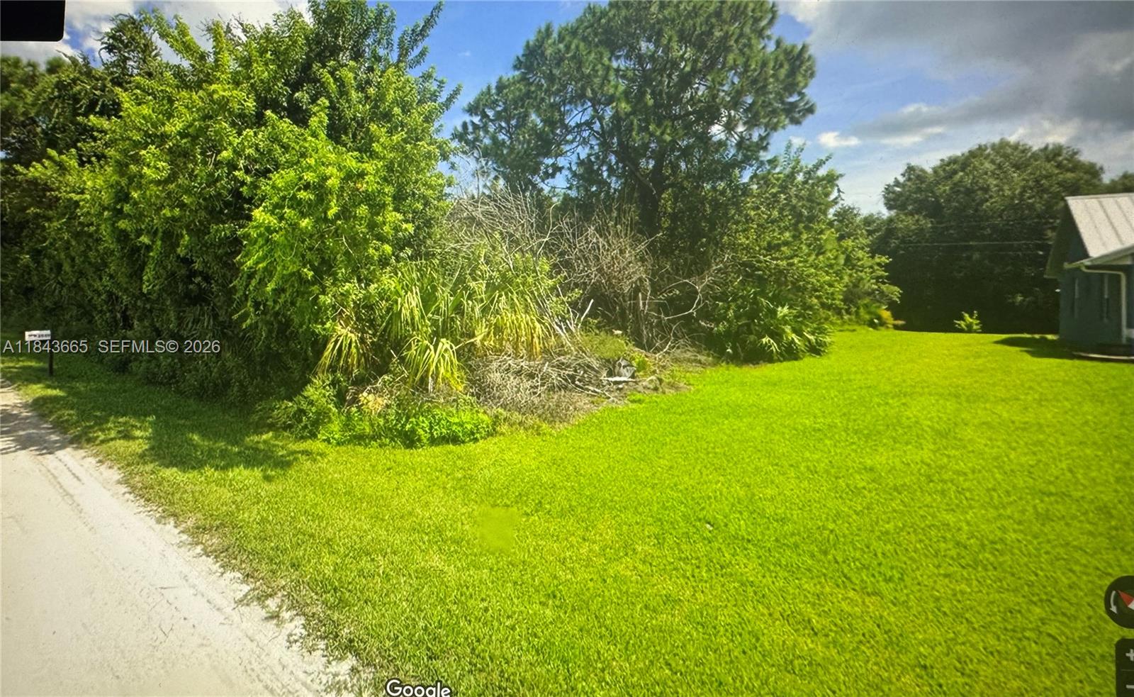 A grassy, undeveloped lot features a cluster of trees and shrubs beside a dirt road — 8966 101st Ct, Vero Beach FL 32967, VERO BEACH, FL