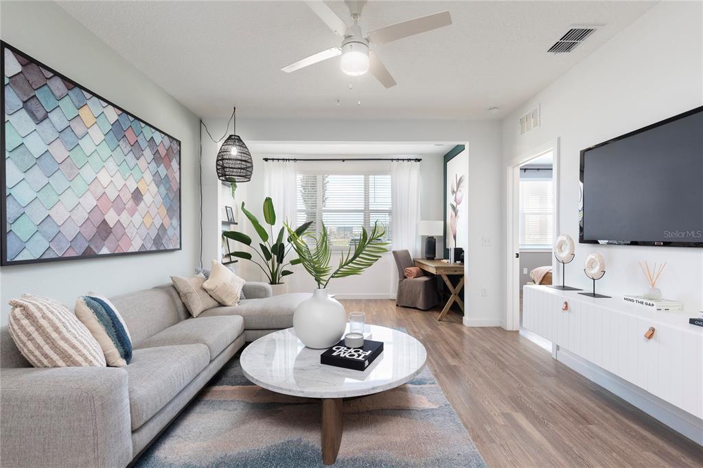 A living room features a gray sectional sofa, a marble coffee table, and a wall-mounted television — 10105 SELTEN WAY, ORLANDO, FL