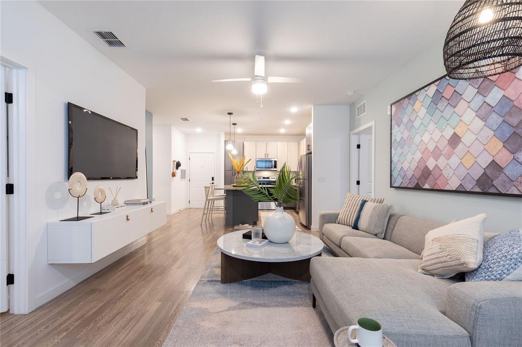 A modern living room features a gray sectional sofa, a marble coffee table, and a television — 10105 SELTEN WAY, ORLANDO, FL