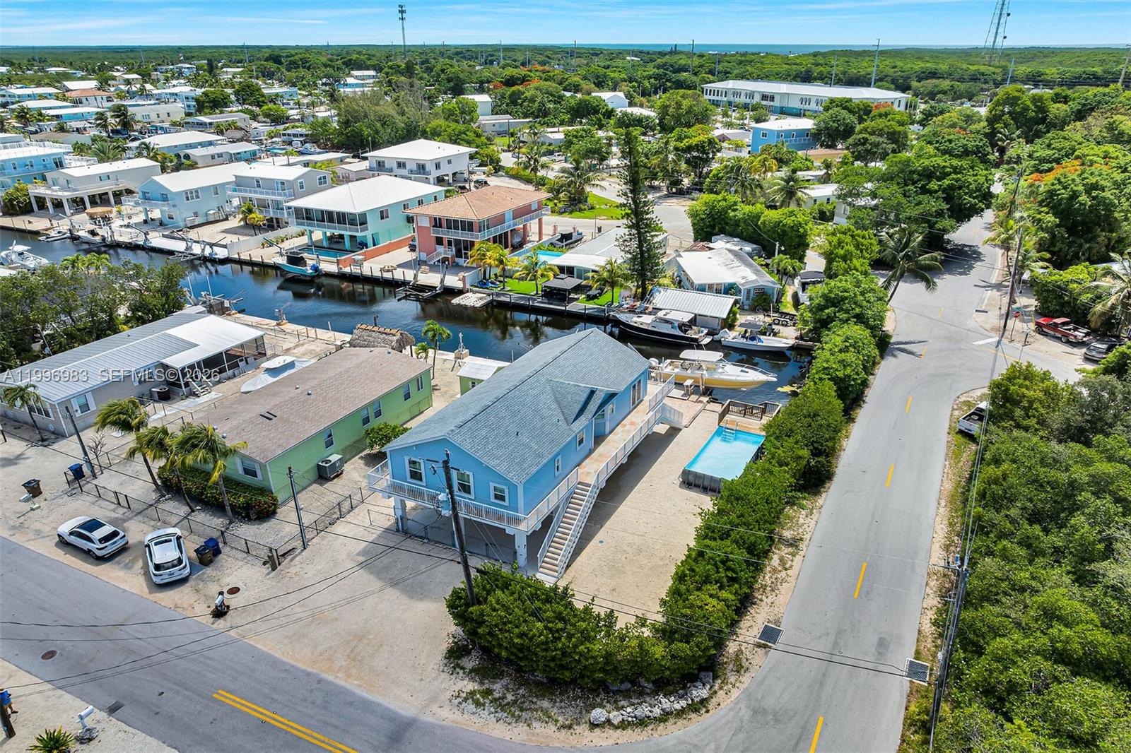 A paved dock features two boat lifts overlooking a canal with several moored boats — 103 Long Key Rd, Key Largo FL 33037, KEY LARGO, FL
