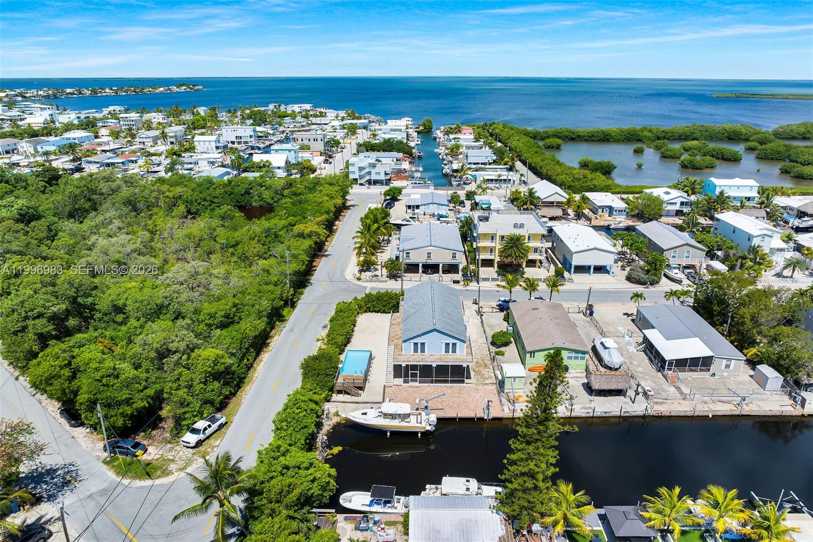 This is a virtually staged, covered outdoor patio featuring wicker furniture and a dining area — 103 Long Key Rd, Key Largo FL 33037, KEY LARGO, FL