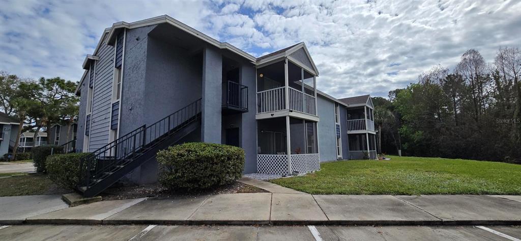 A two-story apartment building with blue siding, exterior staircases, and screened-in balconies — 3814 BAY CLUB CIRCLE UNIT 204, KISSIMMEE, FL