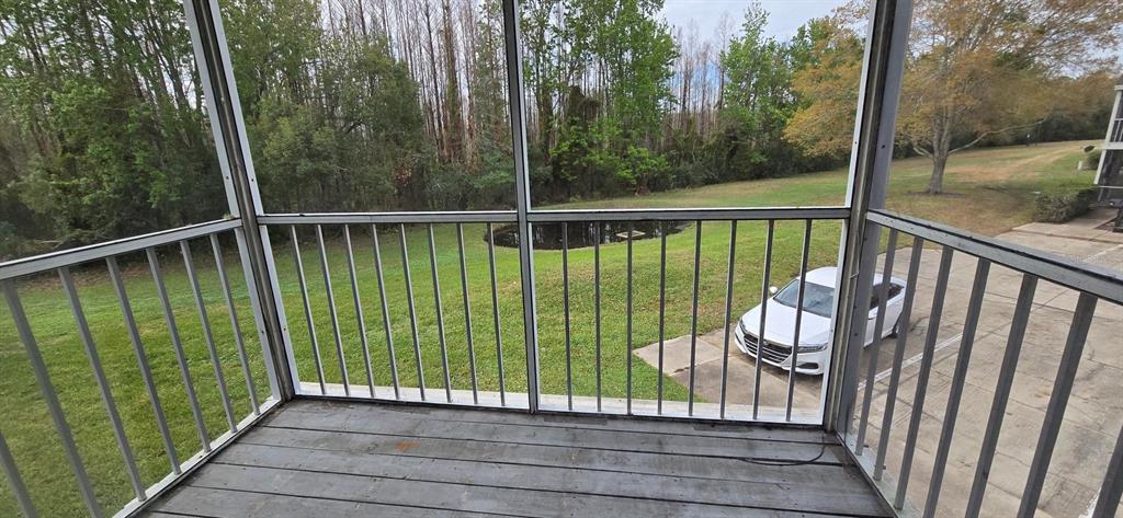 A screened-in balcony overlooks a grassy lawn, a small pond, and a parked car — 3814 BAY CLUB CIRCLE UNIT 204, KISSIMMEE, FL