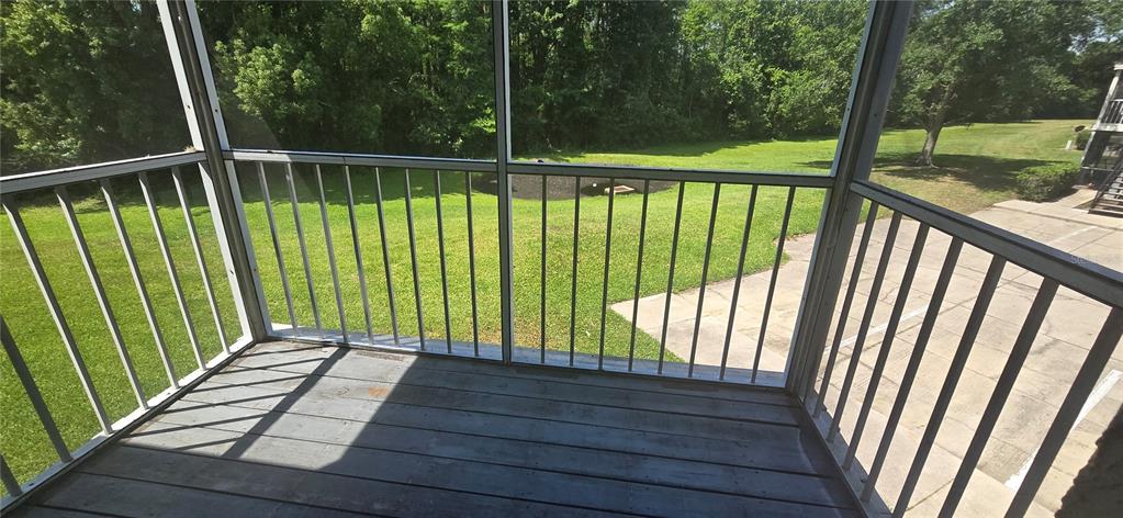 A screened-in porch with a wooden floor overlooks a grassy yard and a paved area — 3814 BAY CLUB CIRCLE UNIT 204, KISSIMMEE, FL