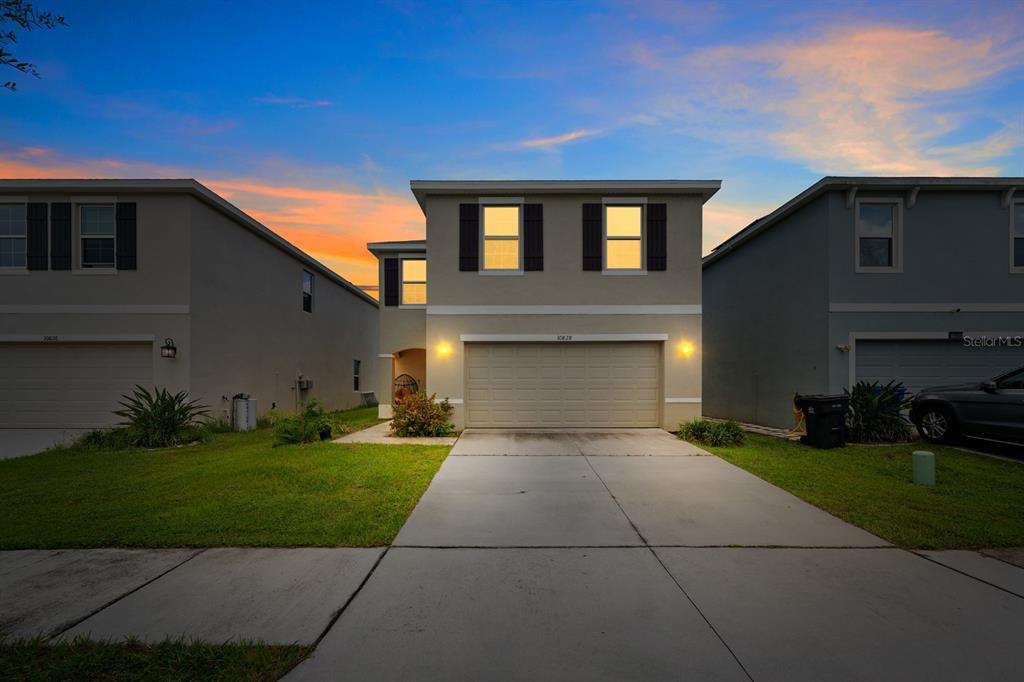 A two-story suburban house with a concrete driveway and a two-car garage at dusk — 10828 TRAILING VINE DRIVE, TAMPA, FL