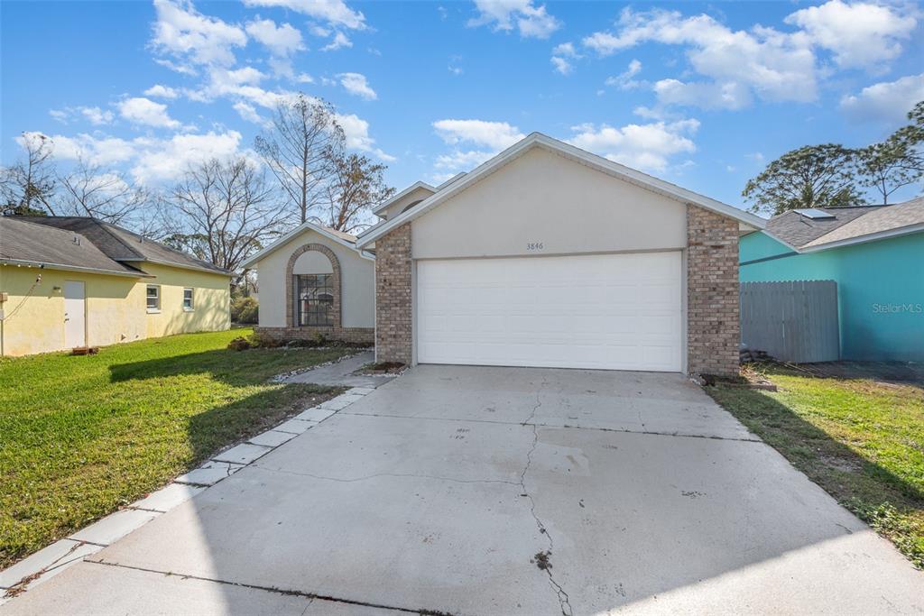 A single-story house with a white garage door, brick accents, and a concrete driveway — 3846 LONG GROVE LANE, PORT ORANGE, FL
