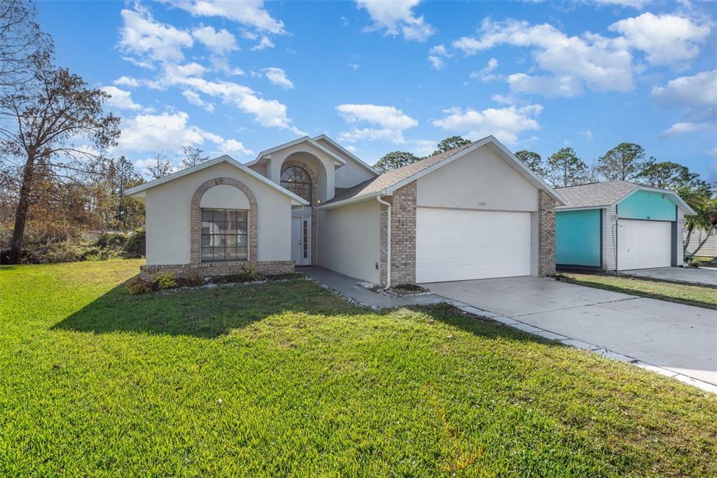 A single-story house with a white stucco exterior, brick accents, and a two-car garage — 3846 LONG GROVE LANE, PORT ORANGE, FL