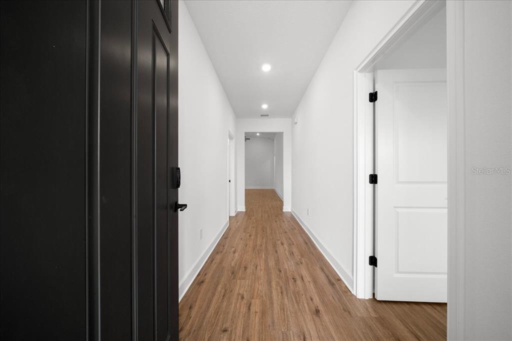 A bright entryway features light wood-look flooring, white walls, and a black front door — 16213 PENN STATE ROAD, WEEKI WACHEE, FL