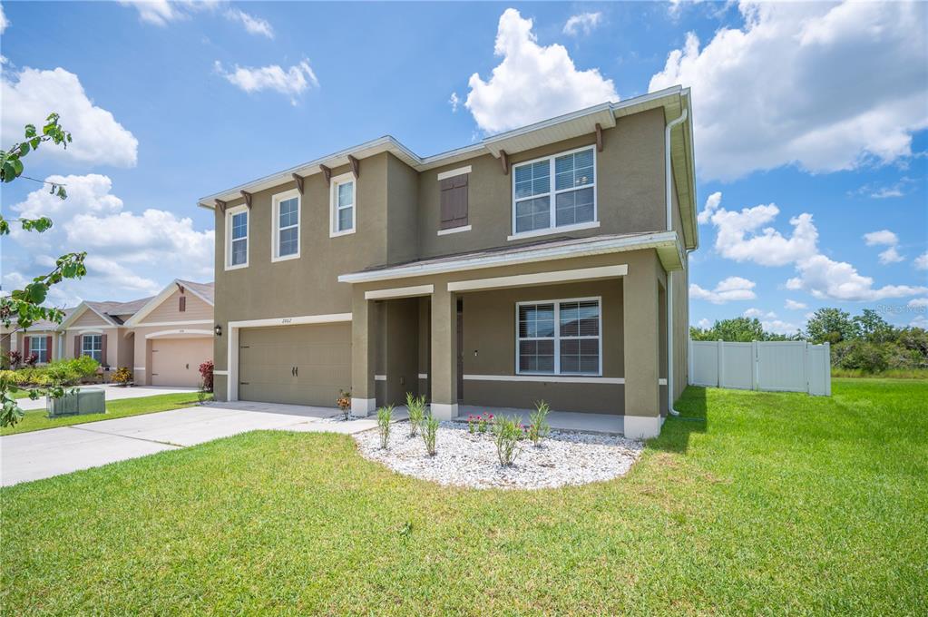 A two-story house with a tan exterior, a two-car garage, and a front porch — 2062 BLUE HIGHLANDS DRIVE, LAKELAND, FL