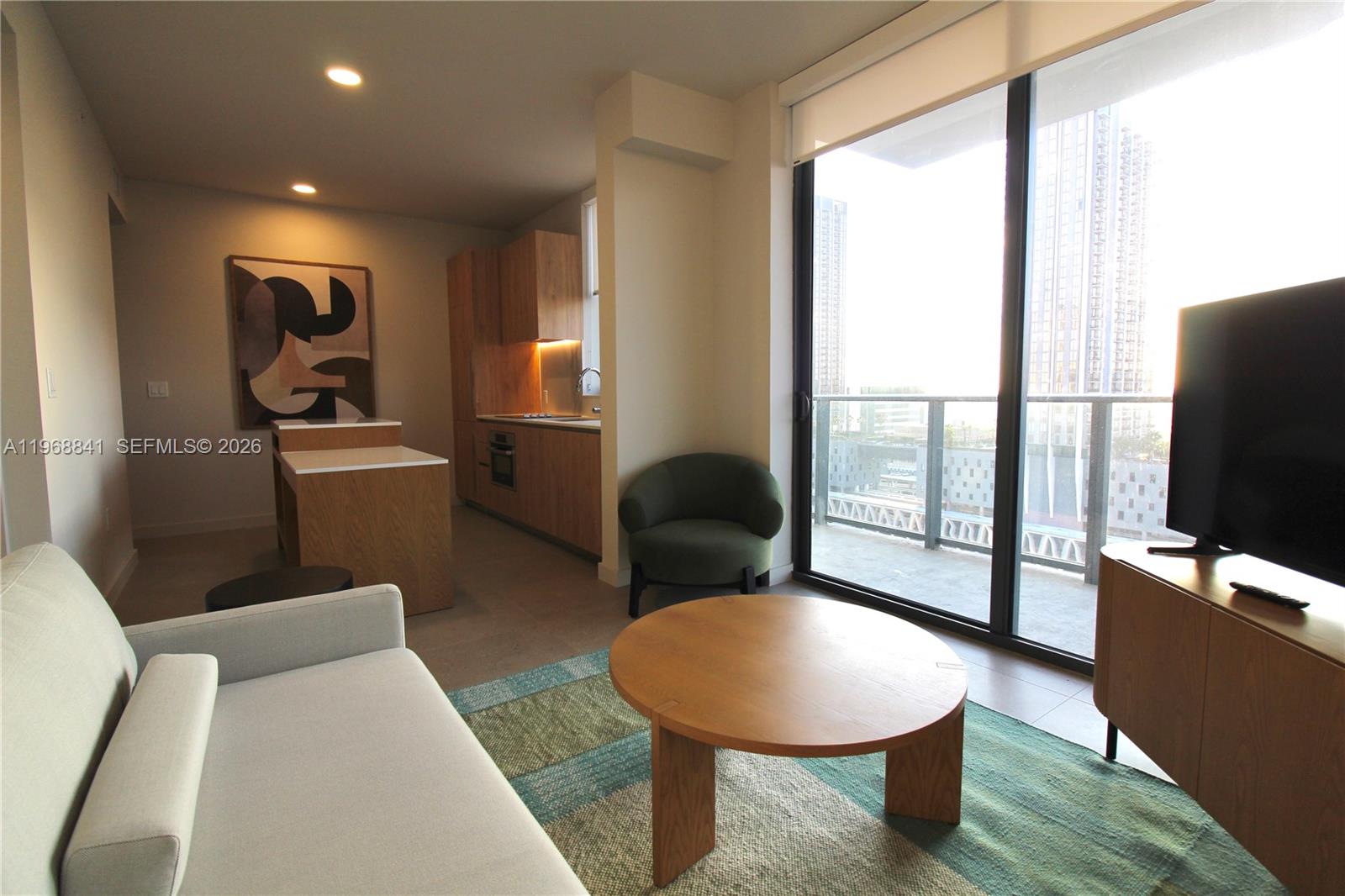 A modern living room features a sofa, round coffee table, and an adjacent open kitchen — 11 NE 6 St # 2114, Miami FL 33132, MIAMI, FL