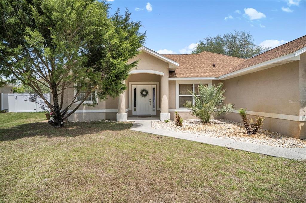 The exterior of a tan, single-story house features a front walkway, landscaping, and a tree — 81 FREEMONT TURN, PALM COAST, FL
