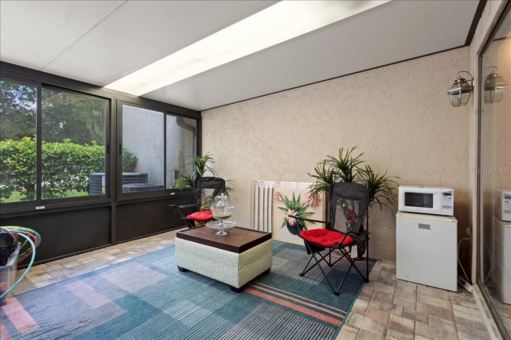 A sunroom features a tiled floor, a large area rug, two chairs, and a microwave — 11418 PALMETTO BOULEVARD, ALACHUA, FL