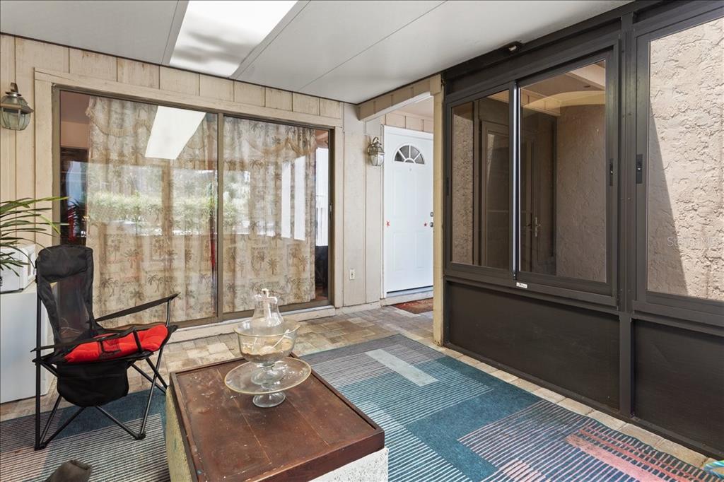 A covered patio features a folding chair, a coffee table, and sliding glass doors — 11418 PALMETTO BOULEVARD, ALACHUA, FL