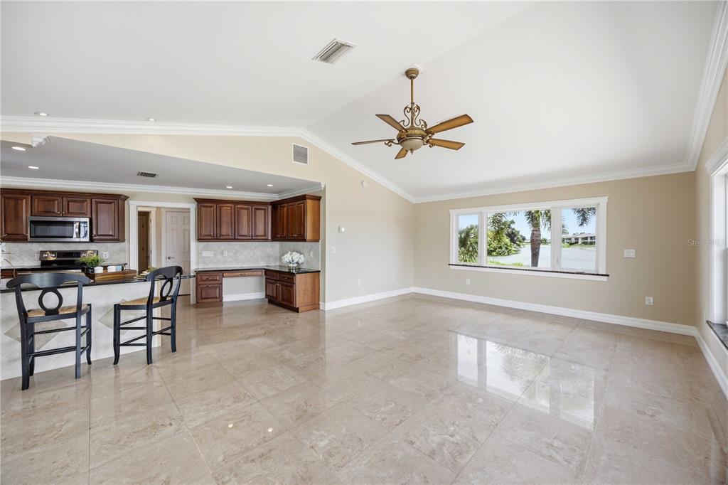 A spacious room with tile floors, a kitchen island, and a large window overlooking water — 1714 CLAW COURT, VENICE, FL