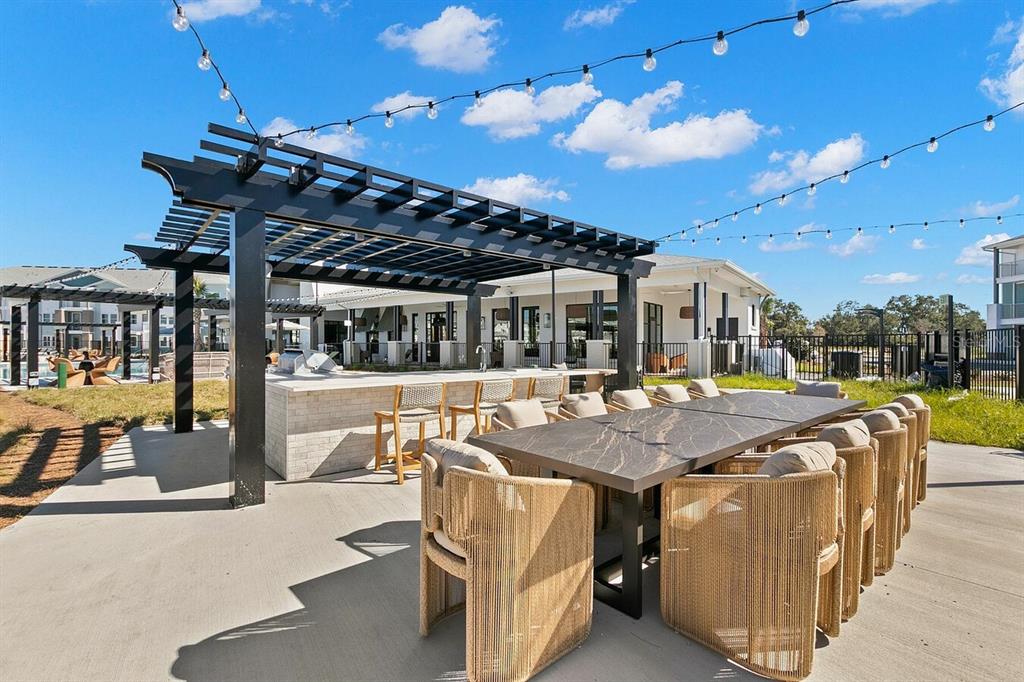 An outdoor patio features a pergola, a stone bar, and a long dining table with chairs — 5476 ANGEL WAY UNIT A1, ST CLOUD, FL