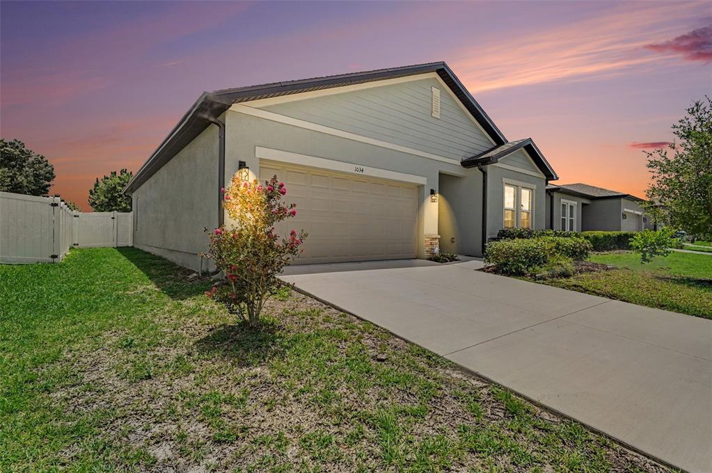 A single-story house with a beige stucco exterior, a two-car garage, and a concrete driveway — 1034 ALABASTER WAY, DELTONA, FL