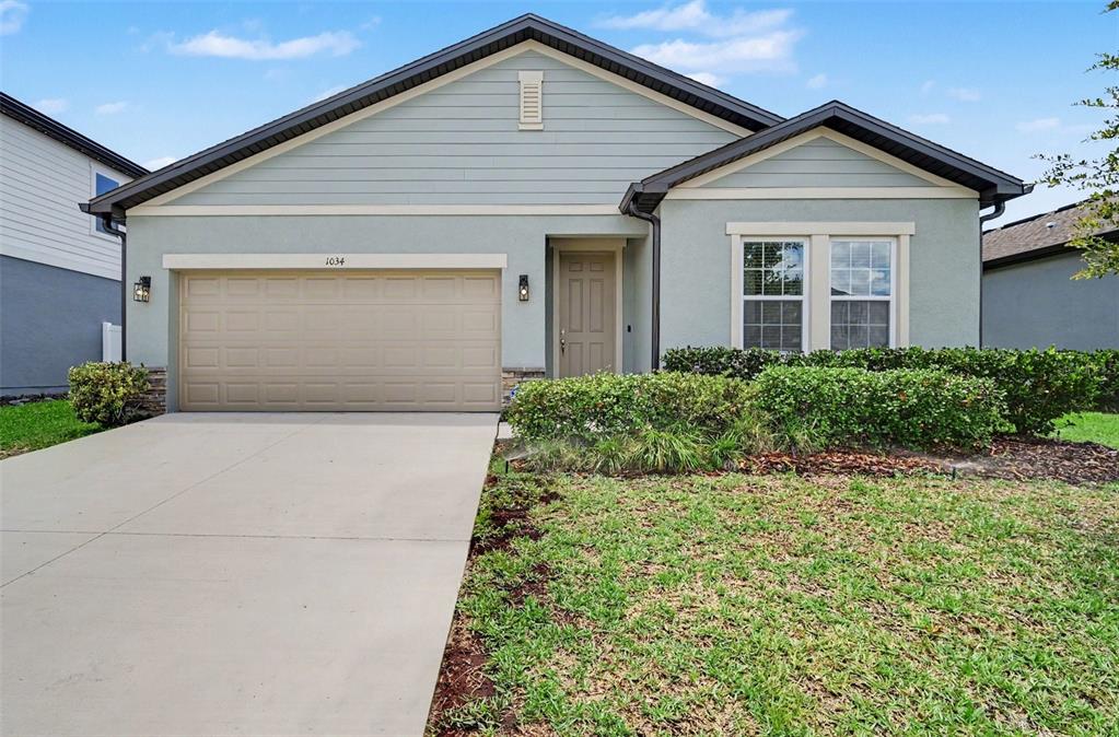 A single-story house with a light green exterior, a two-car garage, and a front lawn — 1034 ALABASTER WAY, DELTONA, FL