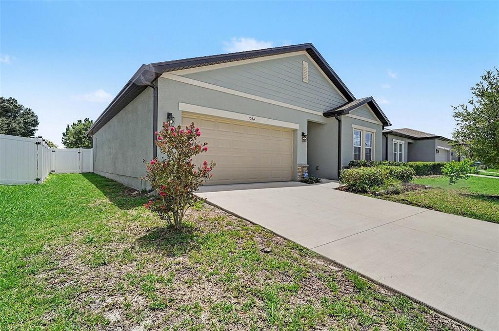 A single-story house with a beige garage, light-colored siding, and a concrete driveway — 1034 ALABASTER WAY, DELTONA, FL