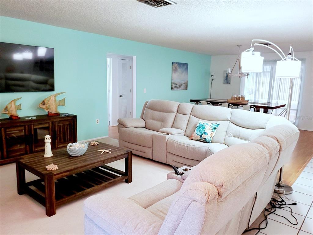 A living room features a light blue wall, a beige sectional sofa, and a wooden coffee table — 2203 43RD STREET W, BRADENTON, FL