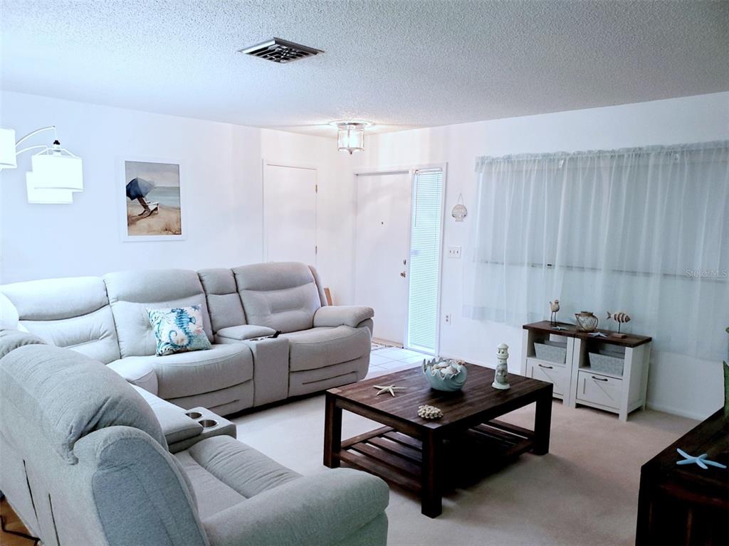 A living room features a light gray sectional sofa, a wooden coffee table, and white walls — 2203 43RD STREET W, BRADENTON, FL