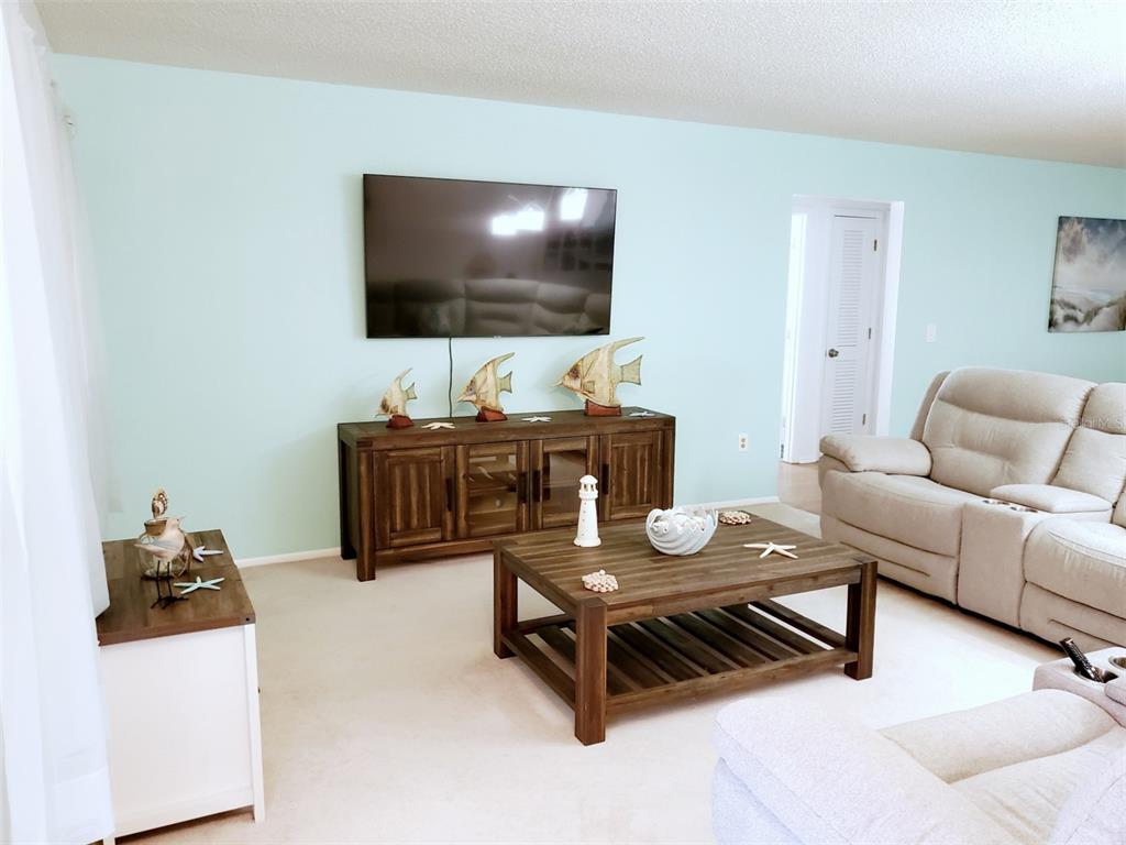 A living room features light blue walls, a wooden media console, and a matching coffee table — 2203 43RD STREET W, BRADENTON, FL