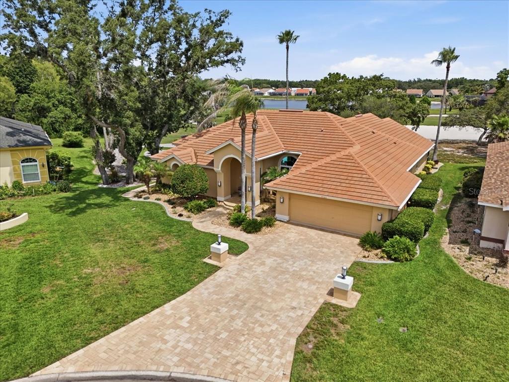 An aerial view of a single-story house with a tile roof and paved driveway — 9161 SOUTHERN COMFORT COURT, WEEKI WACHEE, FL