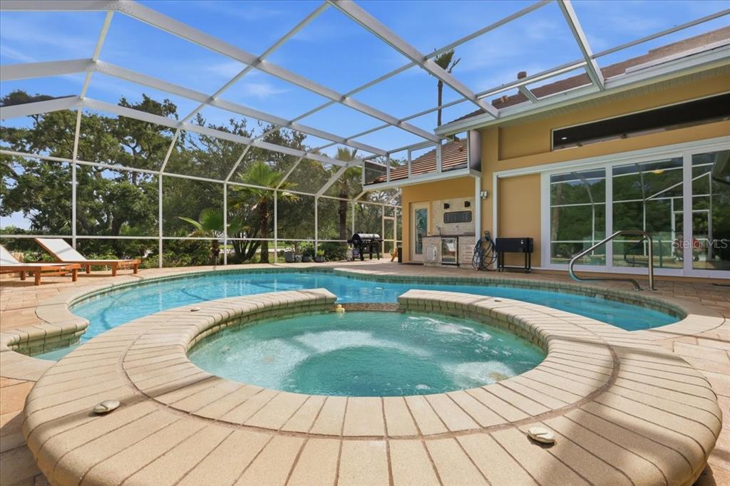 A screened-in patio features a swimming pool, a circular hot tub, and outdoor seating — 9161 SOUTHERN COMFORT COURT, WEEKI WACHEE, FL